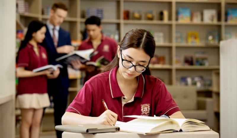Một học sinh lớp 9 đang ngồi tại bàn học, nghiêm túc nhìn vào một tờ giấy ghi kế hoạch ôn tập có đánh dấu các mục tiêu và thời gian biểu, thể hiện sự chủ động trong học tập