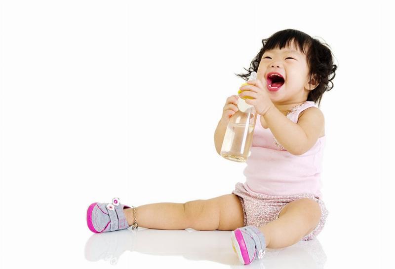 Hình ảnh minh họa một em bé đang đứng cùng mẹ trong bếp, em bé đang quan sát hoặc chạm vào các loại rau củ tươi với vẻ tò mò, thể hiện hoạt động nấu ăn và học hỏi qua quan sát.