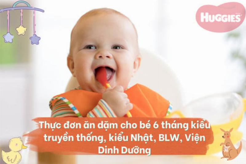 Hình ảnh em bé 6-7 tháng tuổi ngồi ghế ăn dặm, với tay tự cầm một miếng bơ mềm để ăn