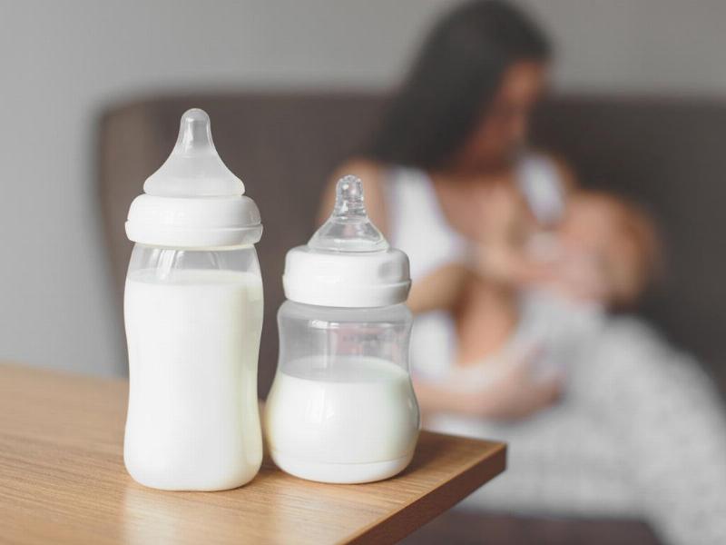 Một em bé 6 tháng tuổi đang ngồi trong ghế ăn dặm, đưa tay ra với lấy một miếng bí đỏ hoặc khoai lang đã nấu mềm, thể hiện sự hứng thú với việc ăn dặm tự chỉ huy (BLW).